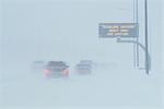Cars on highway in snowstorm advisory sign Anchorage AK/nSouthcentral winter