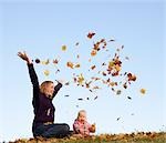 mère et bébé jetant les feuilles d'automne