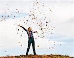 girl throwing autumn leaves into the air