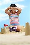 Girl (7-9 years) building sand castles on beach