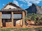 Women pound corn beside a typical double-storied house of the Betsileo people in the Southern Highlands of Madagascar.