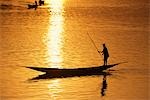 Batelier, promenade en barque son bateau de la poupe au coucher du soleil sur le fleuve Niger