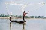 Fisherman cast hand nets on the River Niger from shallow-draught boats