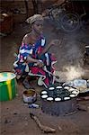 Mali, Bamako, Tinan. Une femme cuisine muffins sur un poêle à côté de la route sur le marché hebdomadaire de Tinan situé entre Bamako et Ségou.