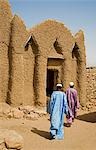 Mali,Gao,Hombori. Two men pass by the imam's house at Hombori which is a traditional mud-brick structure in the Sudanese style of architecture.