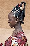 Mali,Gao. A Songhay woman at Gao market with an elaborate coiffure typical of her tribe. The silver coins are old French francs and British West Africa coins dating back one hundred years.