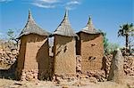 Au Mali, pays Dogon, Koundu. Un petit village construit parmi les rochers près du village Dogon de Koundu. Habitations ont des toits plats alors que les greniers pour stocker millet ont planté des toits de chaume. Les Dogons sont animistes. La butte en terre sacrée à droite avec un œuf d'autruche sur le dessus se trouve un autel utilisé pour les sacrifices par le hogon village ou le prêtre pour apaiser les ancêtres et purifier le village.