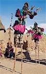 Mali,Dogon Country,Tereli. Masked stilt dancers wearing coconut shells as breasts perform at the Dogon village of Tereli. Tereli is situated among rocks at the base of the spectacular 120-mile-long Bandiagara escarpment. The mask dance is staged at funeral ceremonies to appease the dead and speed them on their way to the ancestral world.