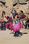 Au Mali, pays Dogon, ce. Un danseur masqué portant des coquilles de noix de coco comme seins effectue dans le village Dogon de ce. C'est situé parmi les rochers au pied de l'escarpement de Bandiagara spectaculaire 120 milles de longueur. La danse des masques est mis en scène lors des cérémonies funéraires pour apaiser les morts et leur vitesse en route vers le monde ancestral.