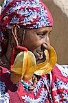 Mali, Mopti. Une femme peule portant de grandes boucles d'oreilles or 14 carats. Kwottenai Kanye boucles d'oreilles sont soit un cadeau de son mari ou hérité à la mort de sa mère. Le haut de chaque boucle d'oreille est lié avec la soie ou de laine rouge pour protéger l'oreille. Les lames des boucles d'oreilles sont magnifiquement sur le modèle.
