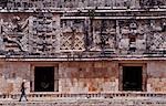 Mexico,Yucatan,Uxmal. A female tourist walks through 'The Nunnery' quadrangle at the Mayan site of Uxmal. This is one of the best preserved Mayan sites displaying the 'Puuc' style of architecture,named after the Puuc Hills nearby.