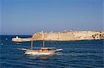 Malta,Valletta. A fishing boat motors out of the entrance to the Grand Harbour past Ricasoli Point.