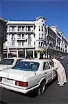 A woman negotiates with a Grand Taxi in front of the faded Art Deco architecture of Boulevard Mohammed V,Casablanca.