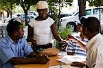 Mozambique,Maputo. A street vendor sells peanuts to clients at a cafe in downtown Maputo. Maputo is the capital of Mozambique. It is a bustling,attractive port city with a population of at least 1.5 million.