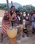 Cheerful young girls pound corn outside their families' homes near Monkey Bay at the southern end of Lake Malawi. Maize meal is the staple diet of Malawians. .