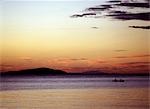 Deux pêcheurs paddle Accueil comme la lueur rouge sang du soleil couchant se reflète dans la vaste mer intérieure du Malawi. .