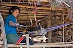 Myanmar, Birmanie, Wan doi. Une fille Ann tissu de tissage au métier à tisser de sa famille situé sous la plate-forme de bambou de leur maison au village de Wan doi.