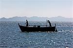 Myanmar,Burma,Sittwe. Fishermen pole a fishing boat in shallow water to Sittwe harbour.