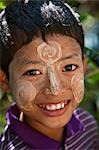 Myanmar,Burma,Kaladan River. A boy of the Rakhine ethnic group decorates his face with Thanakha,a popular local sun cream.