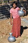 Myanmar,Burma,Mrauk U. A Rakhine girl with aluminium water containers at Mrauk U. These containers are imported from India or Bangladesh.