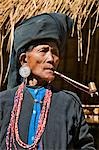 Myanmar,Burma,Rakhine State,Sittwe. An old woman of the small Ann tribe in traditional attire smoking a pipe.