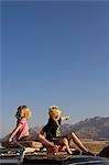 Namibia,Damaraland. With Brandberg Mountain Namibia's highest peak in the background two young children go game viewing from the top of a four wheel drive in late afternoon light.