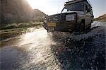 Damaraland, Namibia. Autofahren in ein Allrad Fahrzeug hinunter den Fluß Ugab nahe Brandberg Mountain auf der Suche nach schwer fassbaren Desert Elefanten.