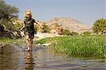 Région de Namibie, Damaraland, Etosha. À la découverte de la région désertique avec de l'eau dans un cours d'eau est une source de joie pour une jeune fille