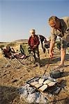 Région de Namibie, Damaraland, Etosha. Famille camping en Afrique, faire griller du pain pour le petit déjeuner sur un feu de camp.