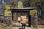 Heavily laden porters enter village gateway,Tal,Marsyandi Valley