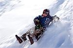 Norway,Tromso,Lyngen Alps. Young boy has extreme fun tobogganing in bright winter son.