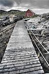 Norway,Nordland,Helgeland. A wooden boardwalk leads from the shore to a small boathouse located above the high water mark