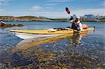 Norway,Nordland,Helgeland. Sea kayaking in coastal Norway during the summer,a guide demonstrated varoius kayaking strokes and techniques in a brightly coloured canoe.