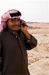 Regana région de Petra, Jordanie. Un guide bédouin habillé en costume traditionnel fait un appel de téléphone mobile depuis les dunes de sable de Regana près de la vallée de la mer morte.
