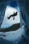 A climber abseils over the mouth of an ice cave at the foot of the Lewis Glacier.