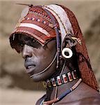 A Samburu warrior resplendent with long,braided,Ochred hair. The braids at the front have been fashioned in a protruding fringe rather like a sunshade. The cloth on top keeps the braids in place. The round ear ornaments of the warriors are made of ivory. Samburu warriors are vain and proud,taking great trouble over their appearance.