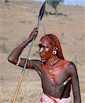 A Samburu warrior resplendent with long braids of Ochred hair. His round ear ornaments are made of ivory. Samburu warriors are vain and proud,taking great trouble over their appearance. They use ochre extensively; it is a natural earth containing ferric oxide which is mixed with animal fat to the consistency of greasepaint. By tradition,warriors always used to carry two spears.