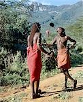 Two Samburu warriors converse,their long braids of Ochred hair distinguishing them from other members of their society. Samburu warriors are vain and proud,taking great trouble over their appearance. An ostrich feather pompom decorates the top of a spear.