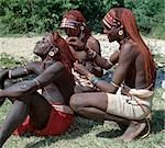 Two Samburu warriors dress the braids of a colleague. Long braids of Ochred hair distinguish warriors from other members of their society. The warriors are vain and proud,taking great trouble over their appearance. Round ornaments,often made of ivory,adorn the pierced and extended earlobes of warriors.