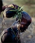 Ein Samburu Jüngling, den Kopf frisch rasiert, hat Milch übergossen ihn aus einem hölzernen Kürbis-wie Container, dekoriert mit grünem Gras vor seiner Beschneidung. Milch und grünem Gras, sind Segen für diese Menschen pastoral und Funktion in allen wichtigen Zeremonien.