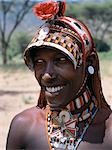 The adornments of Samburu warriors change from generation to generation. In the 1990's cheap plastic flowers from China became fashionable to decorate their Ochred braids. This warrior has had his hair styled in the 'sunshade' look by having his braids at the front combed forward.