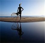 A lone Turkana fisherman with his traditional fishing basket strikes an impressive pose on the shores of Lake Turkana as he waits the arrival of his companions before fishing the shallow waters for tilapia.