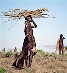 In the semi-arid terrain of Turkanaland,women have to travel great distances to collect firewood. Like other Nilotic people,Turkana women balance heavy loads on their heads with graceful carriage and poise. The attire of this woman is typical of married women in the tribe.