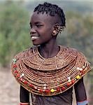 A young Pokot girl in traditional attire. Girls wear leather skirts and capes made from home-tanned goatskins. Her broad necklaces are made from small segments of sedge grass. Her ears have already been pierced in four places,ready to insert the large brass earrings she will acquire after marriage.
