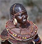 A young married woman of the Pokot tribe. Her married status is denoted by her large brass earrings and broad beaded collars and necklaces that are smeared with animal fat to glisten in the sun.