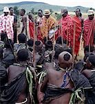 Dressed in his black goatskin cloak,a Samburu boy puts his bundle of sticks,staves and gum on the roof of his mother's house. He has collected these with other boys from a special type of Commiphora tree during an arduous journey on foot of up to 200 miles. After his circumcision,he will make them into bows,blunt arrows and clubs.