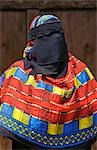 Kenya,Lamu Island,Lamu. A Muslim woman of Lamu town wearing a buibui or face veil with a brightly decorated wrap to offset her black dress.