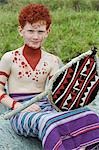 Kenya,Masai Mara National Reserve. A young boy on a family holiday dressed up and painted with ochre in the style of a Maasai warrior .