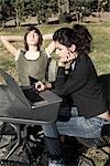 Femme et garçon assis à l'extérieur à l'aide d'ordinateur portable