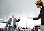Rushing businessman holding up ticket for airline attendant